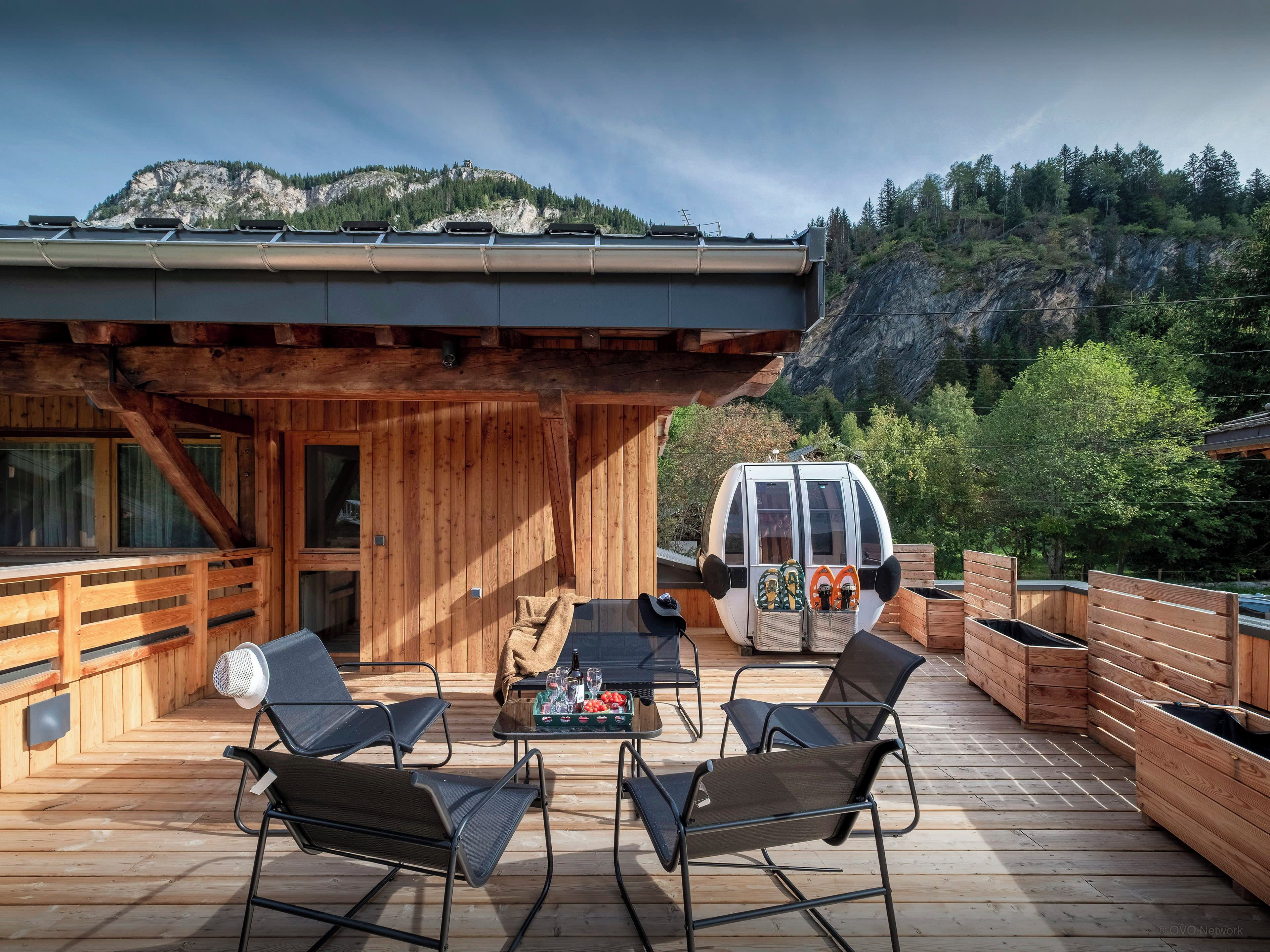 A wooden deck with outdoor seating and a van in the background.