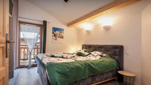A bedroom with a bed, a small round table, a chair, a window with curtains, and a picture on the wall. - Chalet Arpitan Orizon - Chalet in the Vanoise National Park - OVO Network (Pralognan-la-Vanoise)