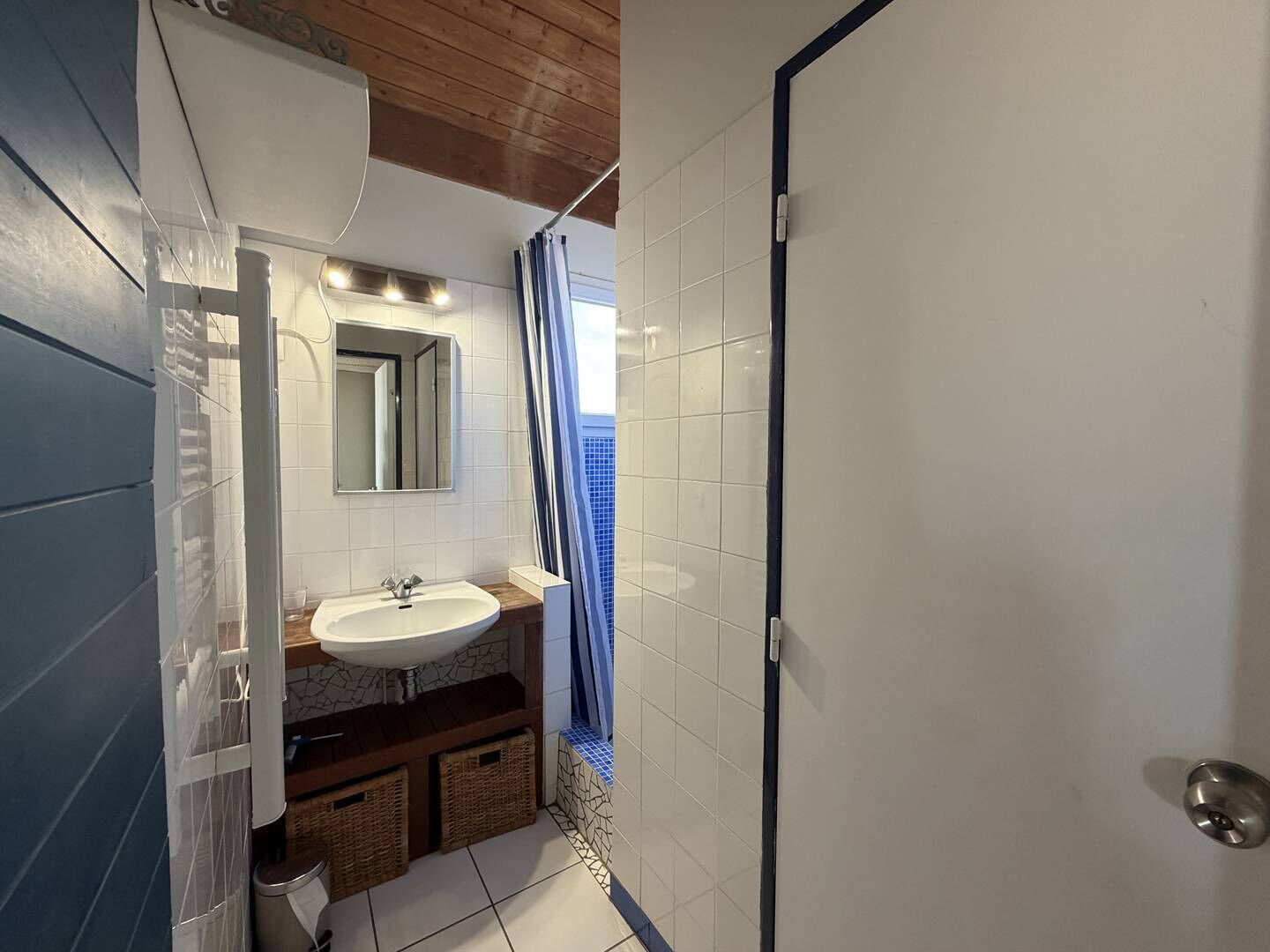 A bathroom with a white sink, a mirror, and a shower curtain.