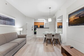 Ein modernes Wohnzimmer mit einer Couch, einem Esstisch, Stühlen und einem Fernseher.