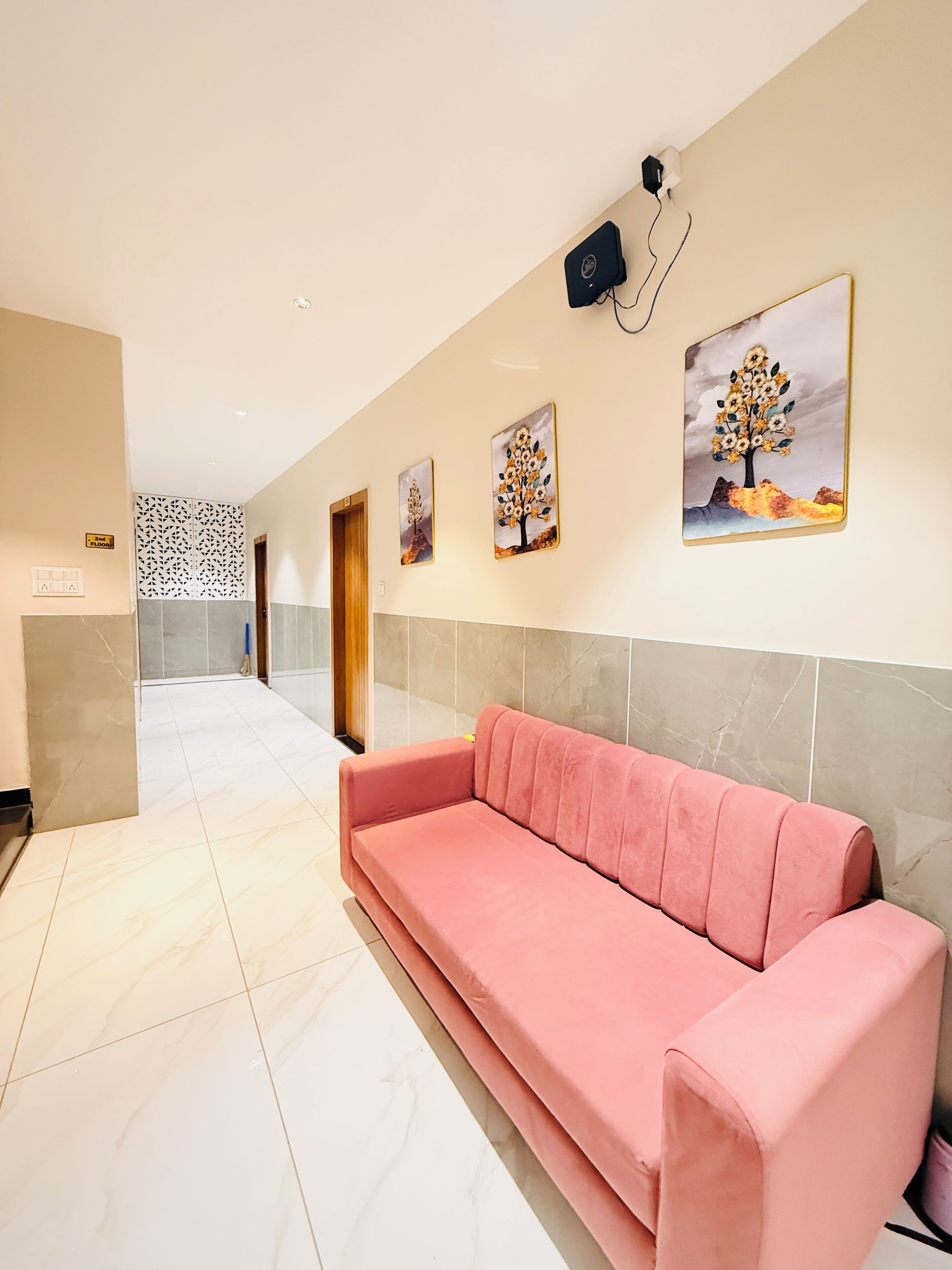 Eine Hotelhalle mit einer rosa Couch, einem gefliesten Boden und Wandbildern.