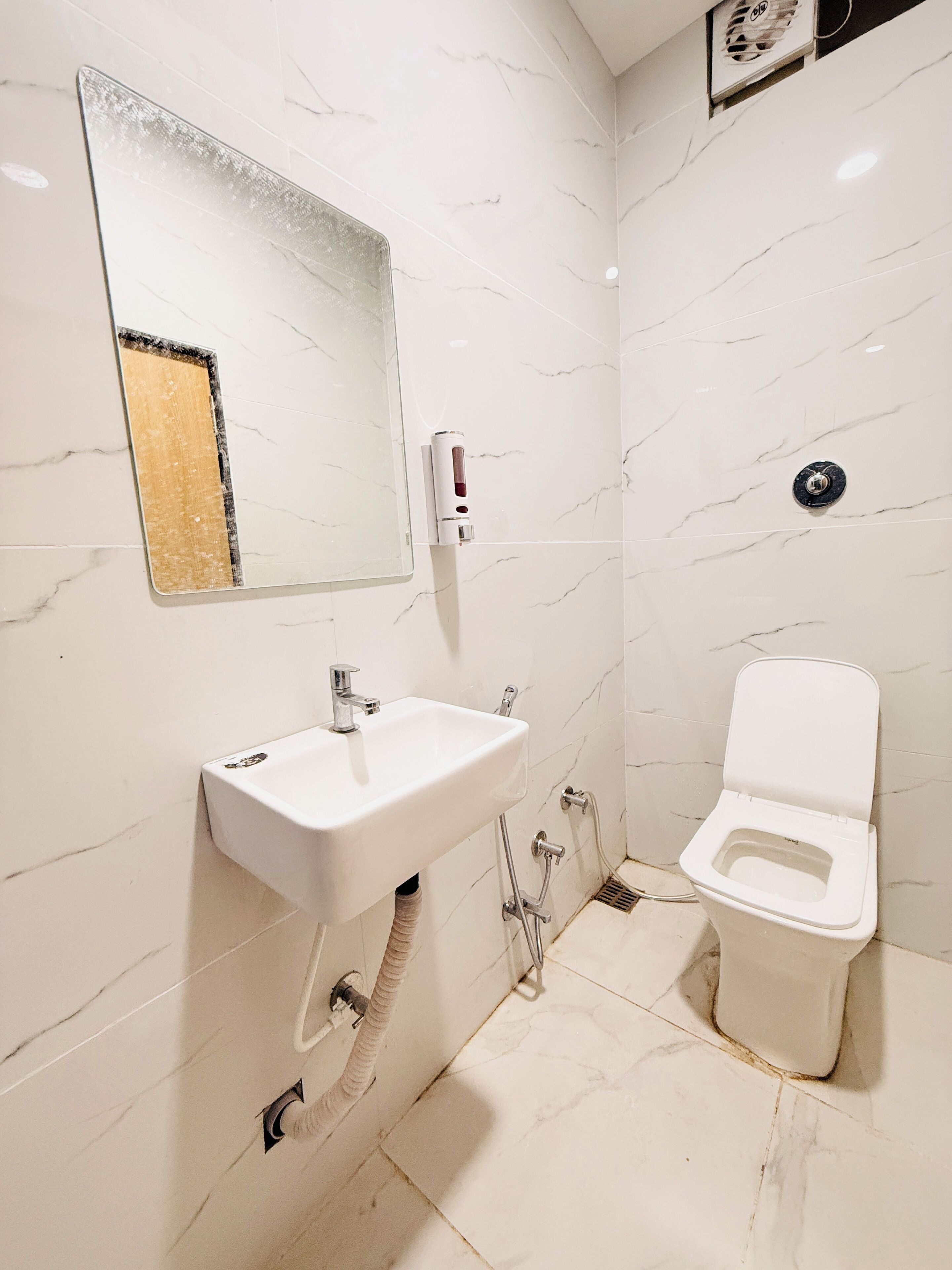A bathroom with a white sink, mirror, and toilet.