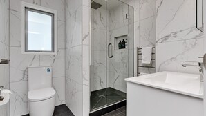 A modern bathroom with a toilet, shower, and sink. - The Lookout Waterfront Apartment at Harbour Lights (One Tree Point)