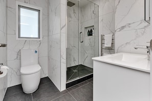 Une salle de bain moderne équipée de toilettes, d’une douche et d’un lavabo.