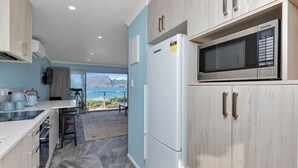 A modern kitchen with a refrigerator, microwave, and cabinets. - The Lookout Waterfront Apartment at Harbour Lights (One Tree Point)