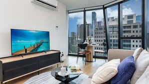 Una sala de estar moderna con un televisor grande, una zona de comedor y un sofá con cojines.