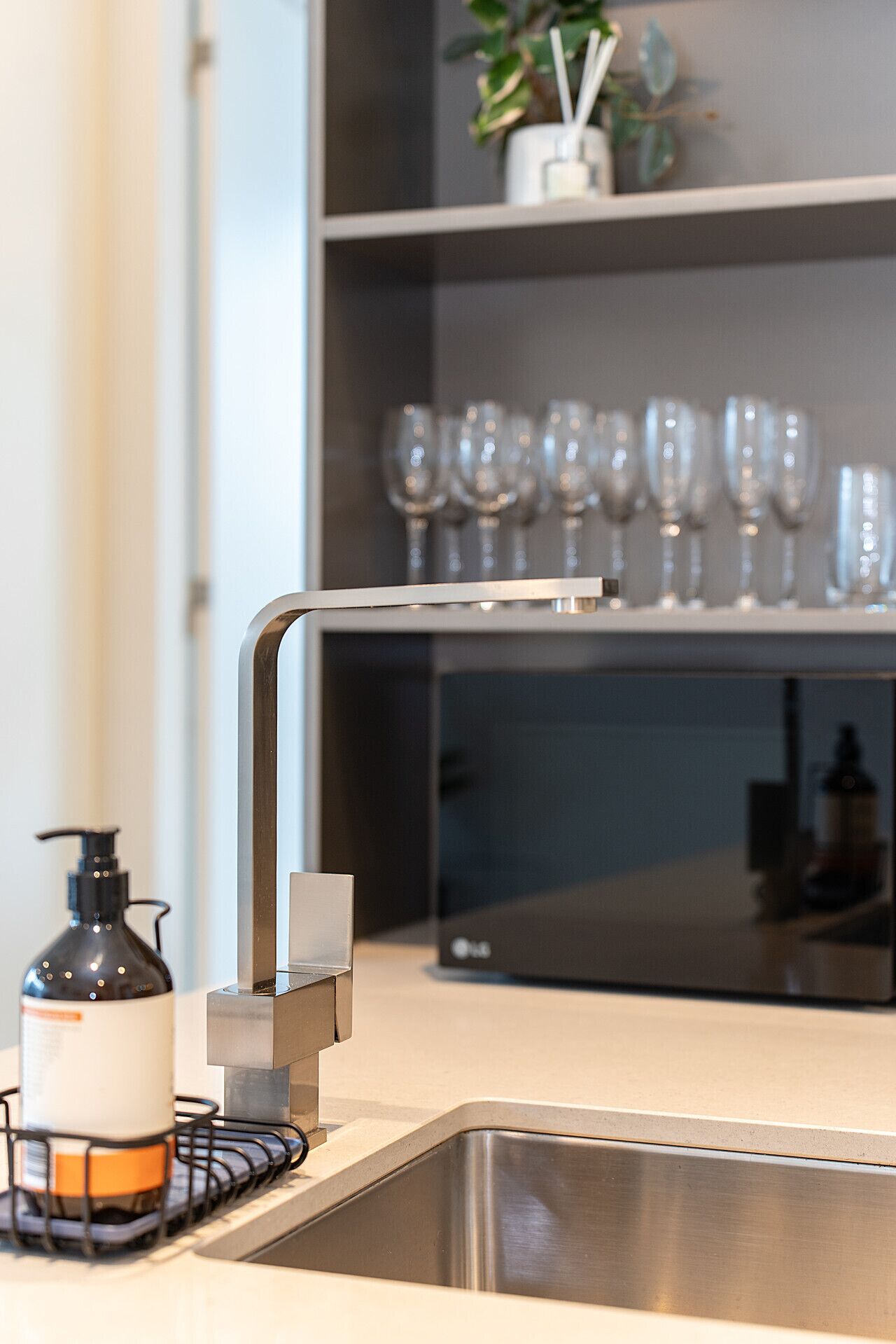 Une cuisine moderne avec un évier en acier inoxydable, un robinet noir et un flacon de savon liquide.
