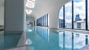 Una piscina interior con ventanas amplias y vistas a la ciudad.