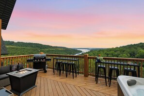 Een terras met een barbecue, zitplaatsen en uitzicht op een rivier.