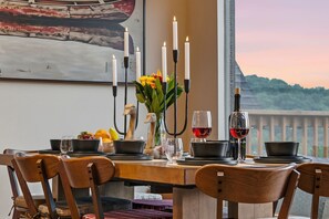 A dining table set with candles, a wine bottle, and a fruit bowl. - BIG Lake View, Private Hot Tub on deck w/Tv & Firepit; High End Design & Comfort (Branson)