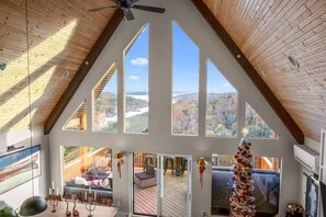 A spacious interior with high ceilings, large windows, and a view of a deck and outdoor area. - BIG Lake View, Private Hot Tub on deck w/Tv & Firepit; High End Design & Comfort (Branson)