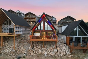 Een modern huis met een houten terras, grote ramen en een stenen fundering.