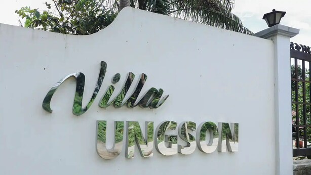 Una pared blanca con el nombre 'Villa Ungeson' en letras grandes y reflectantes.