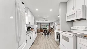 A modern kitchen with white cabinetry, a dining area with a table and chairs, and a ceiling fan. - Indoor Pool, Hot Tub, PT Royale, Bunk Room, LAKE! (Branson)