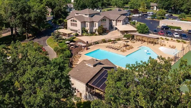 A residential area with a large swimming pool, multiple houses, and a hilly landscape in the background. - Indoor Pool, Hot Tub, PT Royale, Bunk Room, LAKE! (Branson)