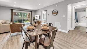 A modern living room with a dining area, a large window, and a view of the outdoors. - Indoor Pool, Hot Tub, PT Royale, Bunk Room, LAKE! (Branson)