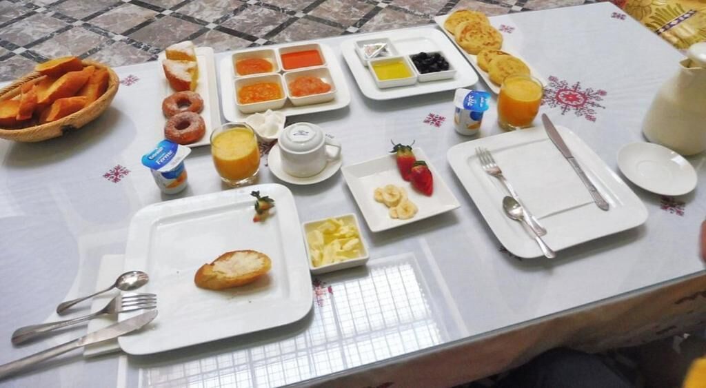 Un bufé de desayuno con diversos platos y utensilios sobre una mesa.