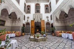 Un patio con detalles de azulejos intrincados, una fuente central y zonas de estar.