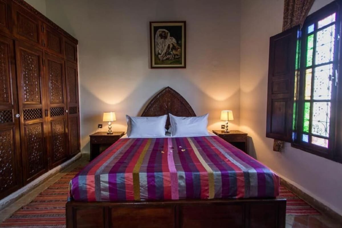 Una camera da letto con un letto grande, due comodini, un armadio in legno e una finestra con vista.