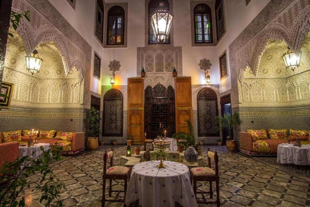 Un patio interior con arcos ornamentados, una fuente central y zonas de estar.