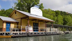 Un edificio frente al agua llamado 'Fall Creek Marina', con una terraza cubierta y un letrero que indica que está abierto al público.
