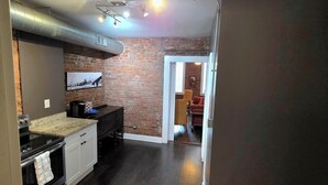 Una cocina con pared de ladrillo, televisor de pantalla plana y piso de madera oscura.