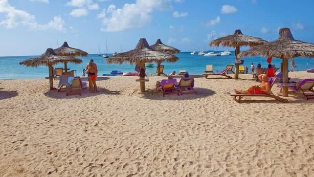 A beach with thatched umbrellas and sun loungers, a clear sky, and boats in the water. - Unit 6 Coast Luxury Town Homes  Newly Refurbished (Rodney Bay)