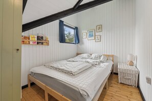 A bedroom with a wooden bed, a small bedside table, a lamp, and wall-mounted pictures.