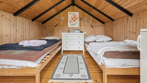 A cozy attic bedroom with two wooden bunk beds, a white dresser, a framed poster on the wall, and a small table with a lamp. - Charming holiday home near beach and town (Dronningmølle)
