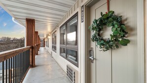 Un corridoio coperto con ringhiera in legno, una porta con il simbolo del numero e un'ghirlanda.