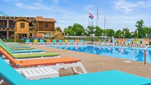 Una piscina con comode poltrone colorate e un edificio con un'area giochi.