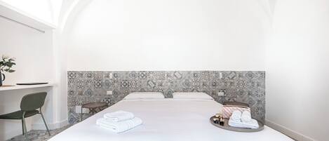 Habitación de hotel con una cama grande, un escritorio y una silla. Hay toallas y artículos de aseo en la cama.