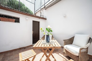 Eine Terrasse mit Tisch, Stühlen, einer Blumenvase und einer Tür.