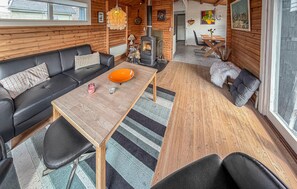 A cozy cabin interior with a wooden dining table, black leather sofa, and a fireplace. - Nice home in Broager with WiFi (Broager)