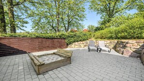 An outdoor patio with a wooden hot tub, two lounge chairs, and a stone wall. - 4 bedroom nice home in Nordborg (Nordborg)