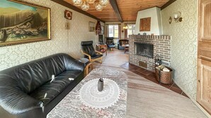 A living room with a leather sofa, a fireplace, a clock, and a painting on the wall. - 4 bedroom nice home in Nordborg (Nordborg)