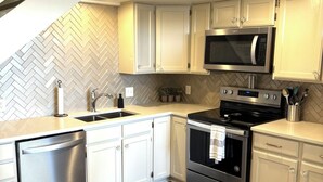 A modern kitchen with white cabinets, stainless steel appliances, and a herringbone-patterned backsplash. - Marvelous studio apartment with pickleball court in welcoming Orem neighborhood (Orem)