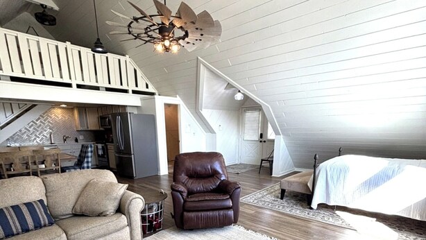 A spacious loft with a high ceiling, exposed wooden beams, a dining area, a leather chair, and a large bed. - Marvelous studio apartment with pickleball court in welcoming Orem neighborhood (Orem)