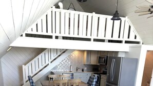 A living room with a sofa, a dining table, chairs, a kitchen area, and a staircase. - Marvelous studio apartment with pickleball court in welcoming Orem neighborhood (Orem)
