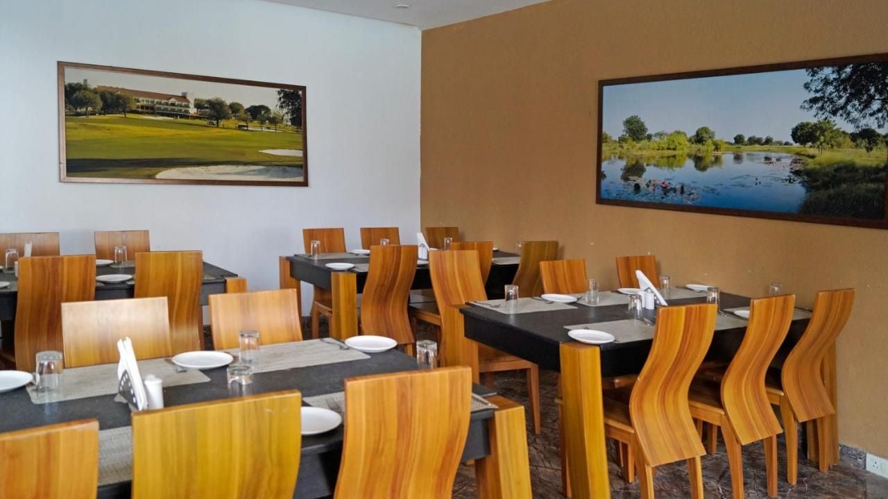 Un comedor con varias mesas y sillas, pinturas de paisajes en las paredes y un diseño moderno y cuidado.