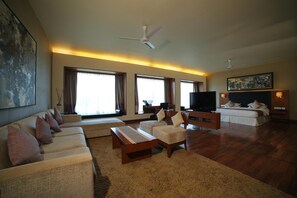 A spacious living room with a sofa set, a television, and a bed. - Club Mahindra Kensville Golf Resort (Bavla)
