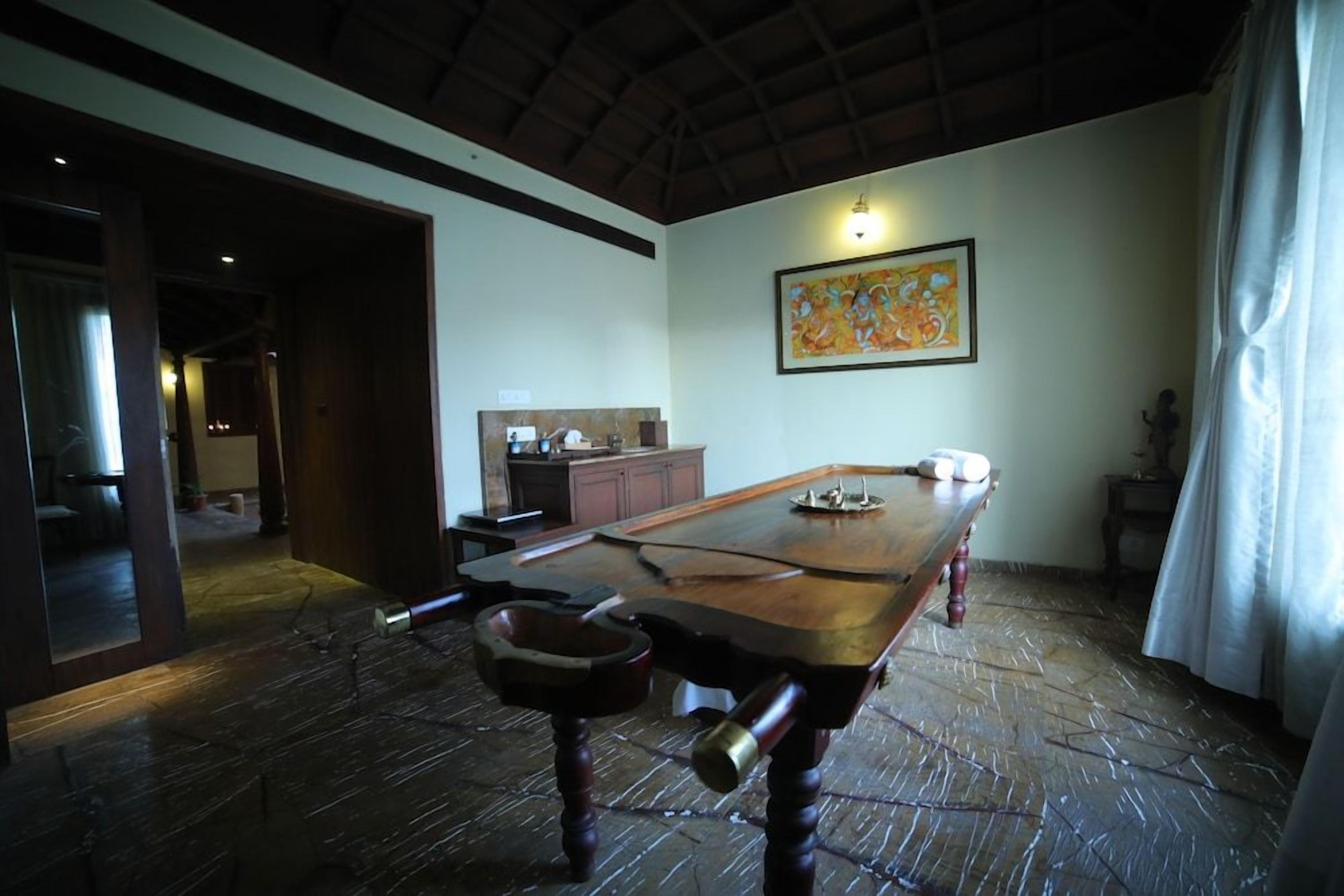 A dining area with a long wooden table, a bench, and a painting on the wall.