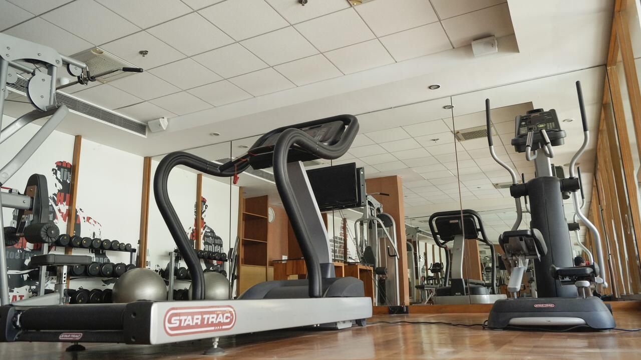 Ein Fitnessstudio mit Cardiogeräten, Kraftmaschinen und einer Spiegelwand.