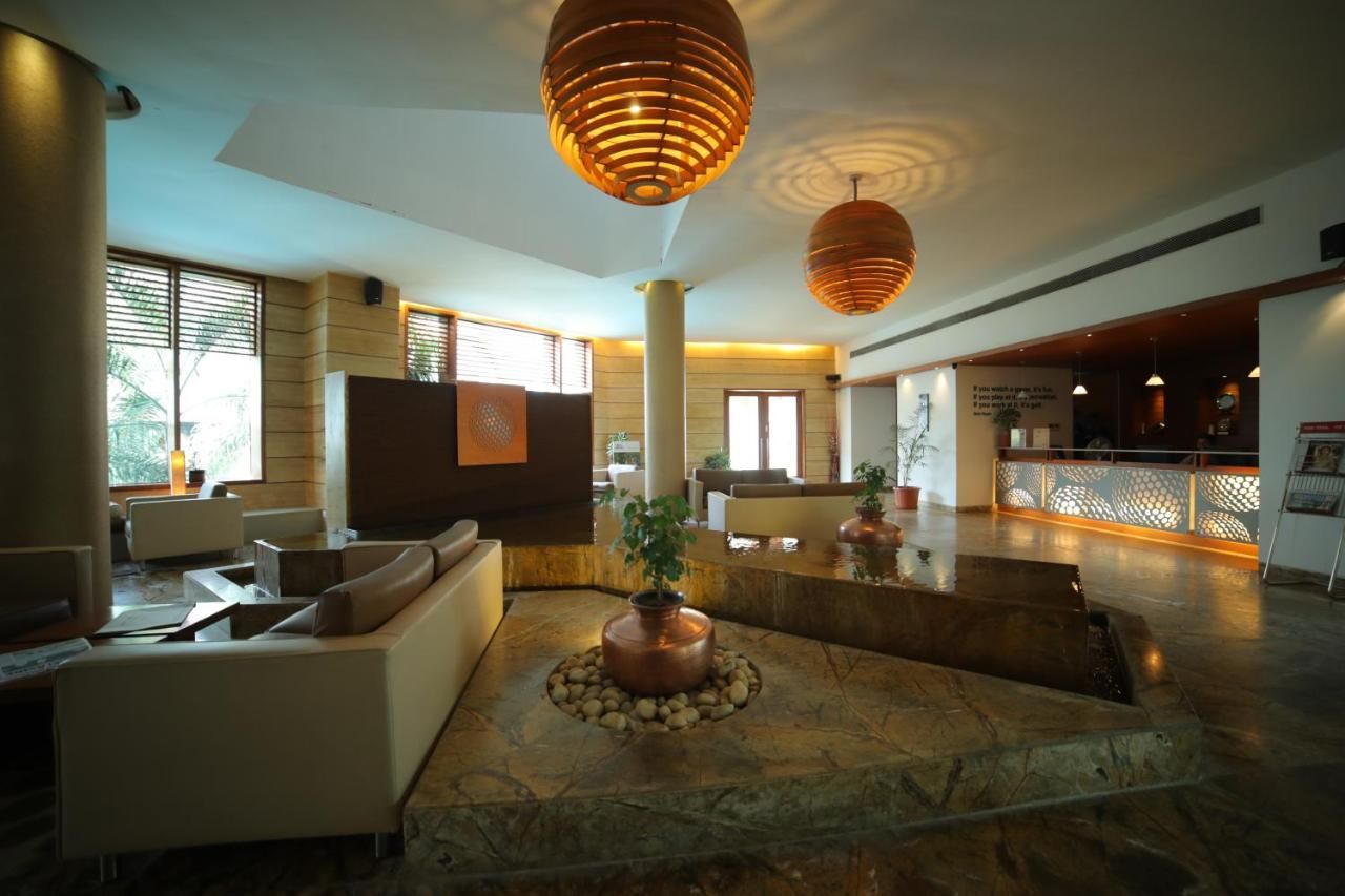 A spacious lobby with modern furniture, a central water feature, and a reception desk.