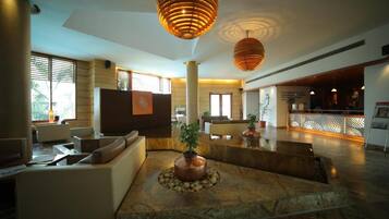 A spacious lobby with modern furniture, a central water feature, and a reception desk.