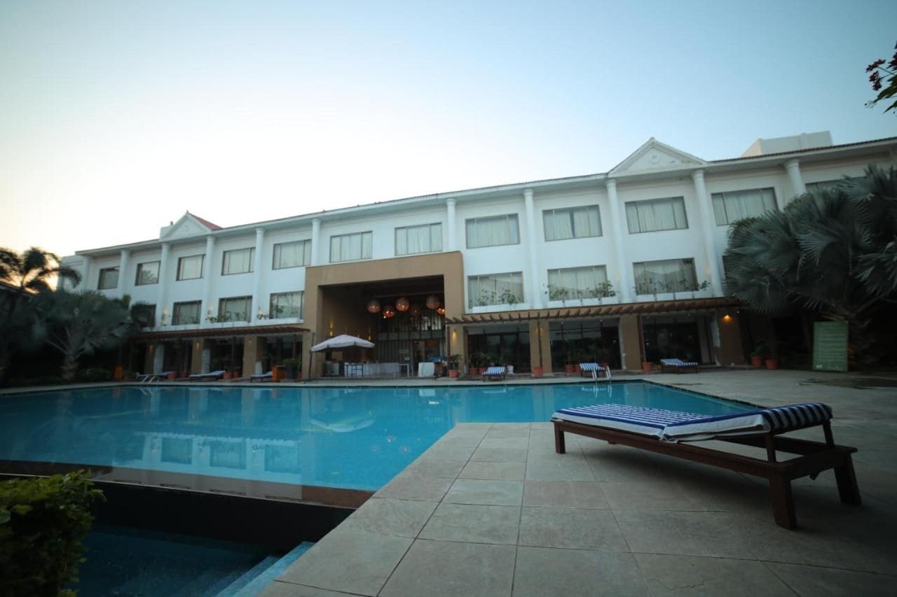Un hotel con piscina, sillas de descanso y una zona cubierta con sombrillas.