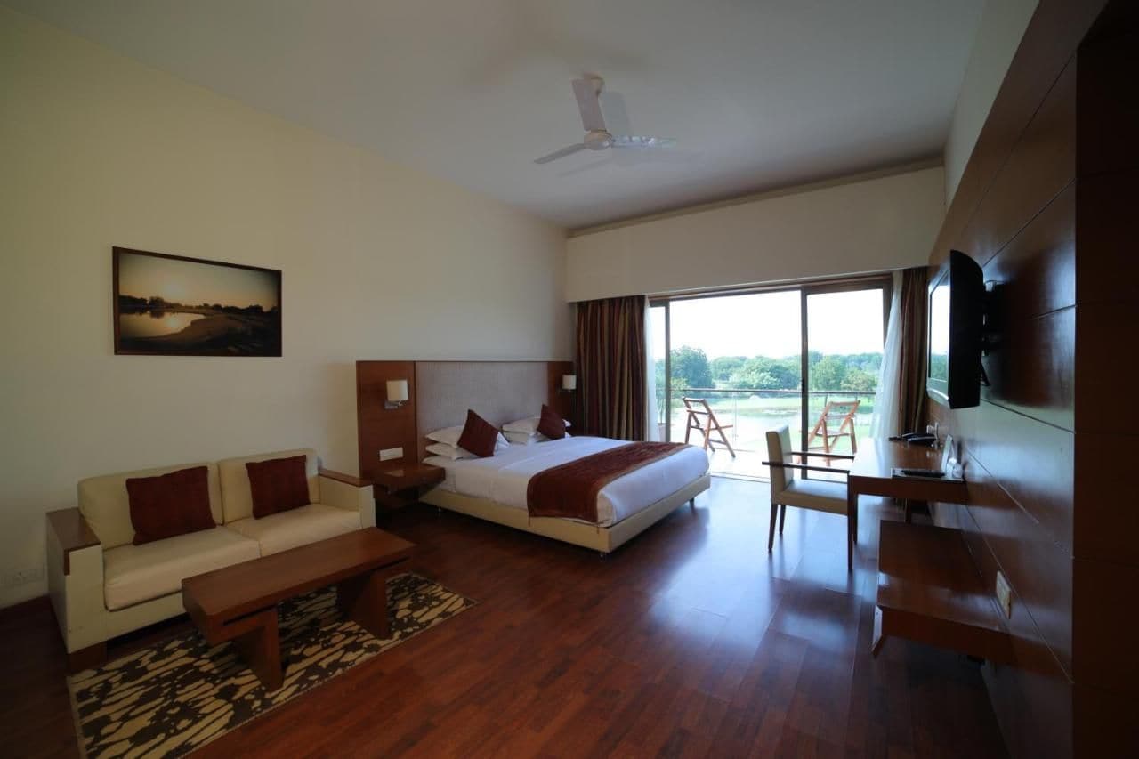 Ein modernes Hotelzimmer mit Bett, Sofa, Schreibtisch und einem großen Fenster mit Blick ins Freie.