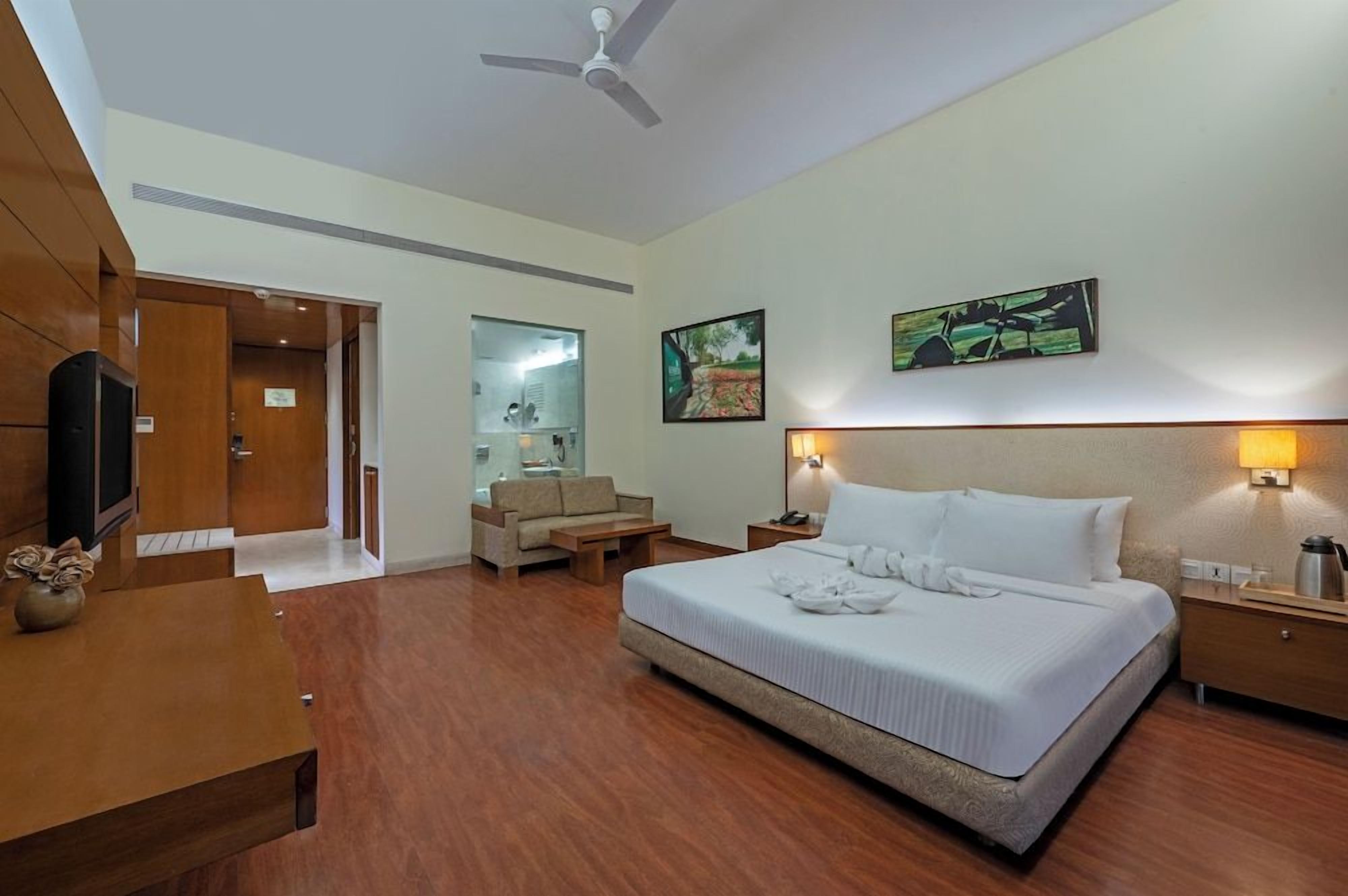 A hotel room with a bed, bedside table, lamp, and a television.