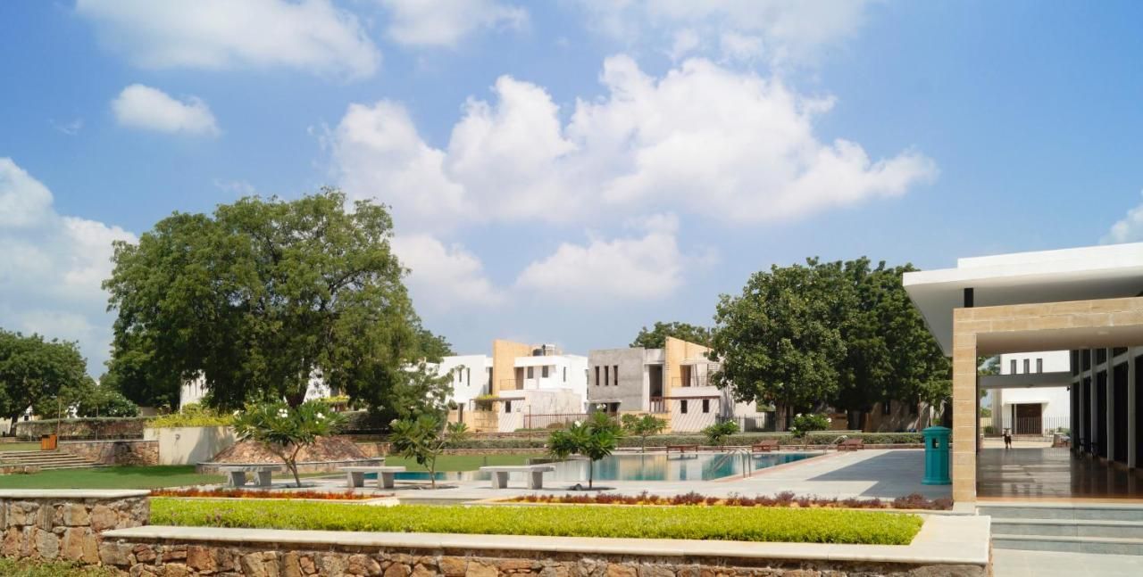 A modern building with a pool, stone walls, and greenery.