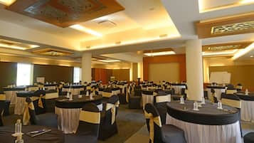 A conference room with round tables, black chairs with gold sashes, and a whiteboard.